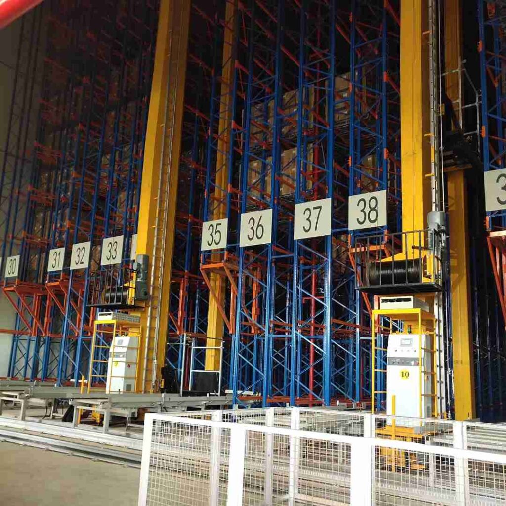 An automated narrow aisle crane operating inside a high-bay narrow aisle racking for cold storage facility at freezing temperatures.