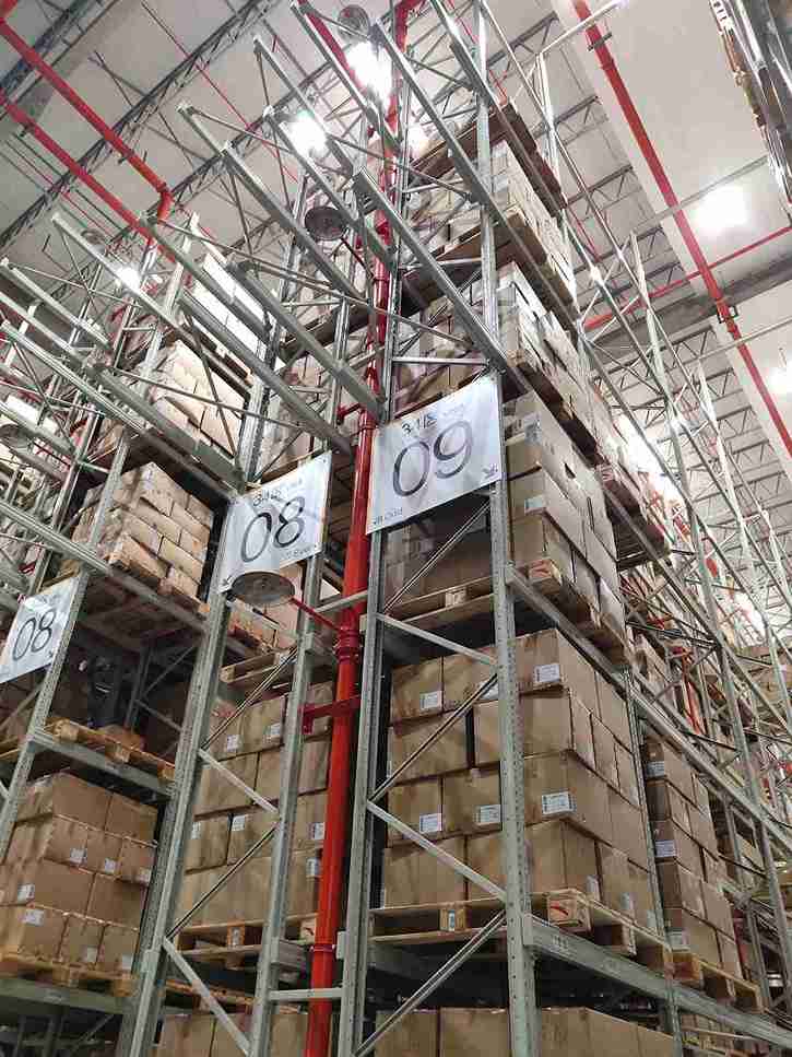 Engineer measuring pallet specifications to select the correct forklifts for narrow aisle racking in a warehouse