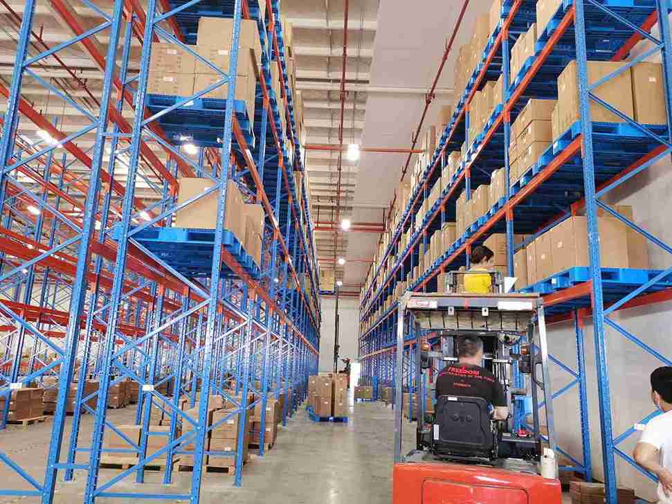 Forklift safely loading pallet onto secured pallet rack wire dividers with high kick plates
